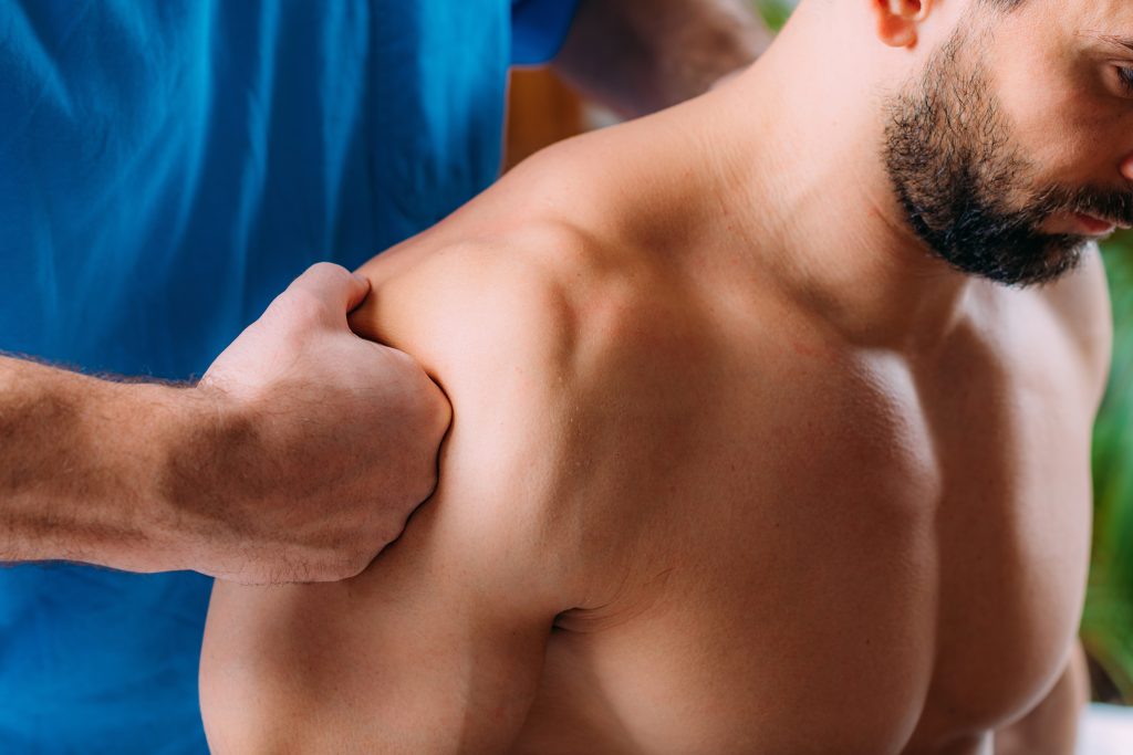 Physiotherapeut massiert Schulter des Patienten