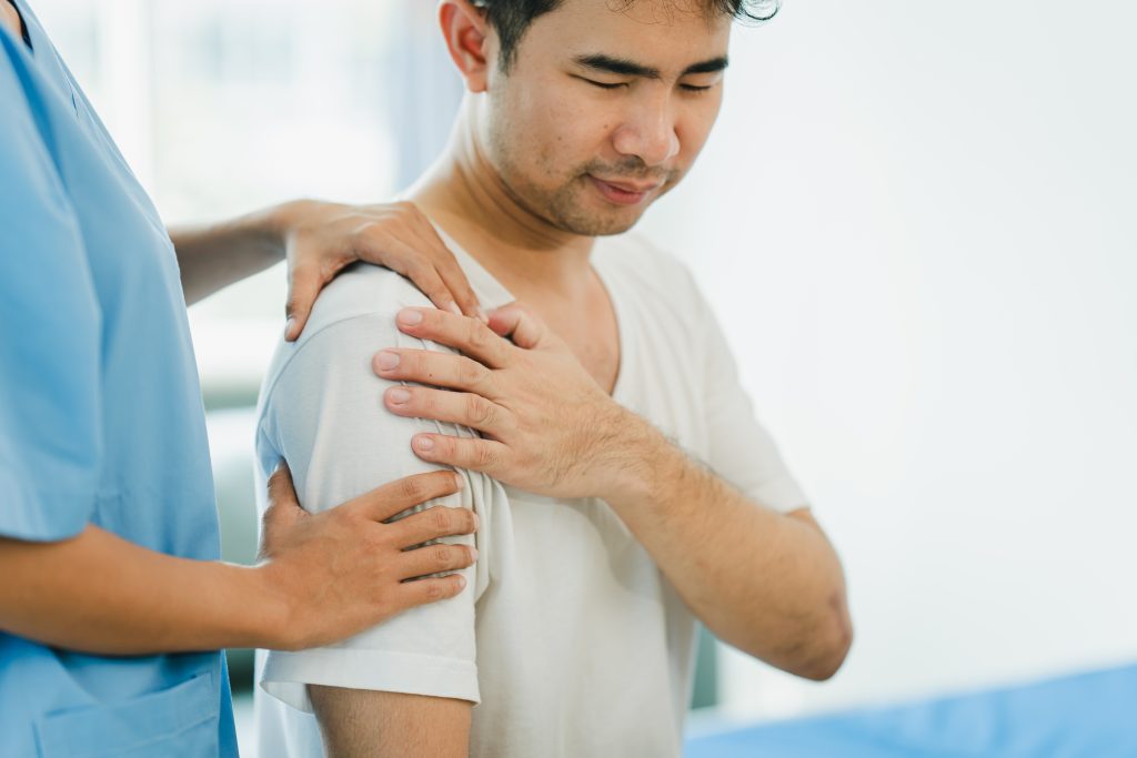 Patient greift sich an Schulter wegen Schmerzen