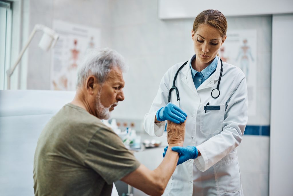 Ärztin überprüft Hand von älteren Patienten